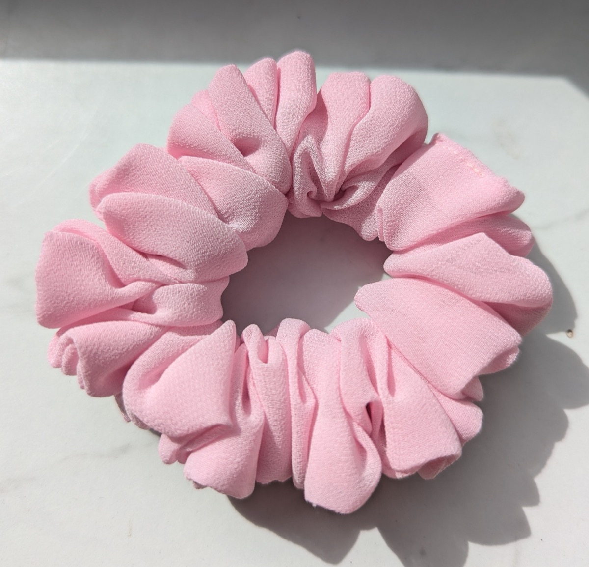 Handgenähter Scrunchie in Rosa, auf hellem Untergrund fotografiert