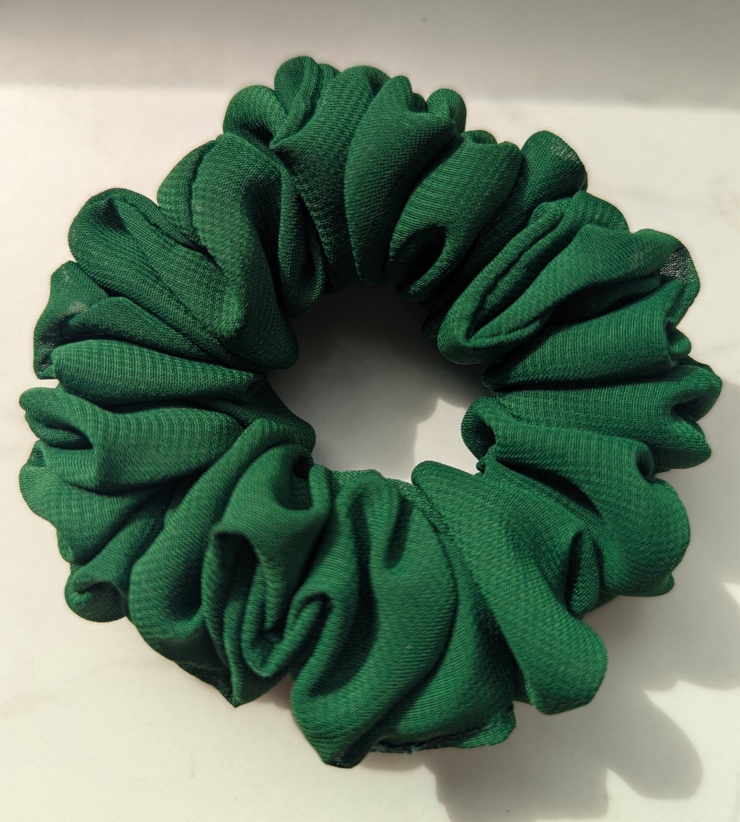 Handgenähter Scrunchie in Dunkelgrün, auf hellem Untergrund fotografiert