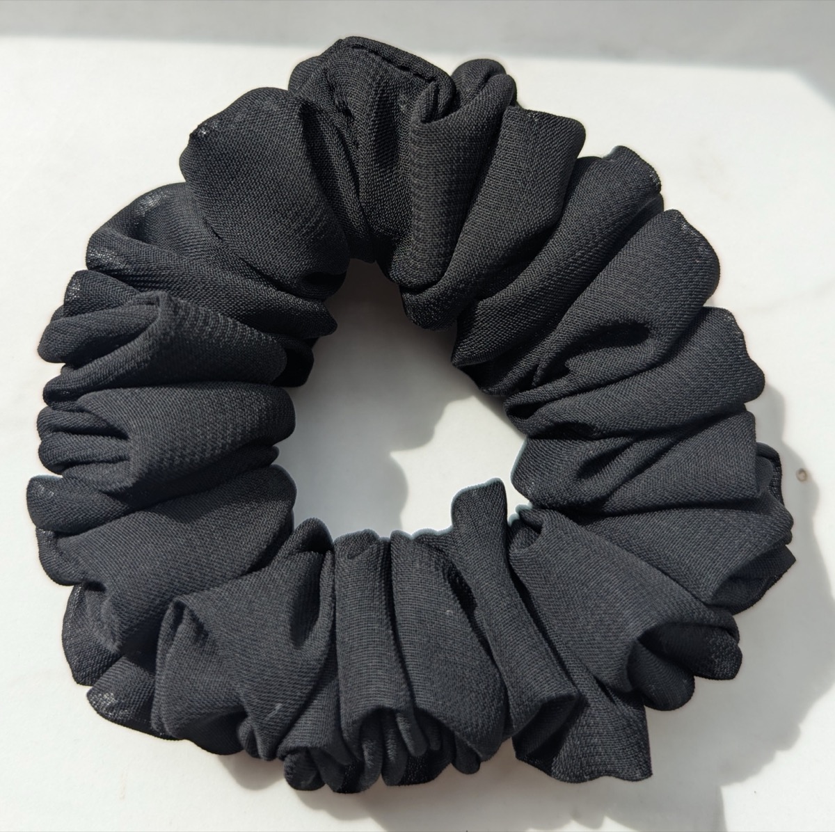 Handgenähter Scrunchie in Schwarz, auf hellem Untergrund fotografiert